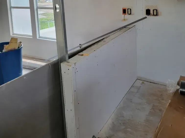 Partition wall framed with a steel stud and new drywall, outlet boxes exposed before the wall is closed