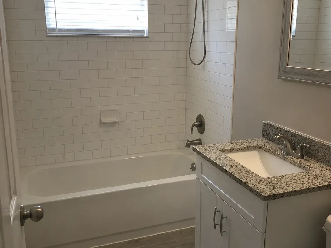 Refitted guest bathroom with a tub, subway tile surround and a new vanity with a granite top