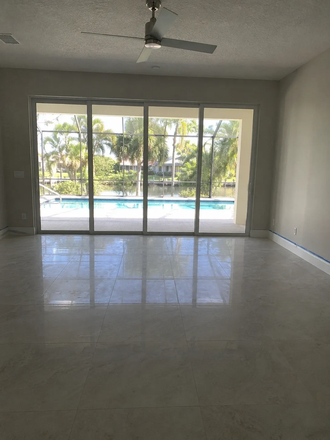 Former lanai converted to conditioned living space, tile floor running to new sliders overlooking the pool cage