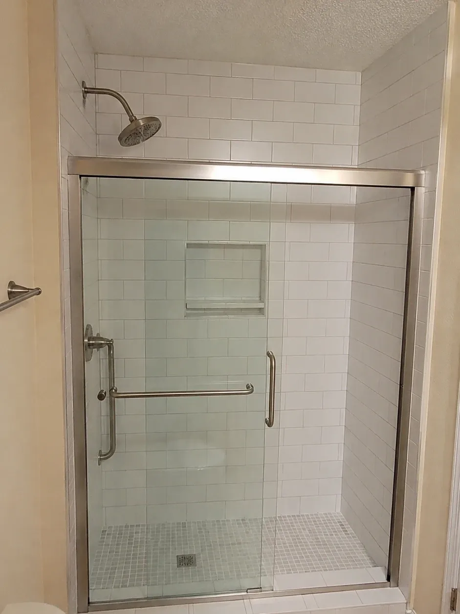 Former tub alcove converted to a walk-in shower with subway tile, a storage niche and a sliding glass door